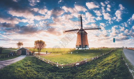 荷兰日出时的风车令人惊叹的景观与传统的荷兰风车,绿色的草,栅栏五颜六色的天空与云乡村景观与复古色调夏天的乡村场景图片
