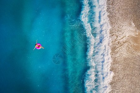 鸟瞰轻女子游泳粉红色的游泳环透明的绿松石海,土耳其奥卢德尼斯夏天的海景与女孩,美丽的波浪,蔚蓝的水阳光明媚的日子图片