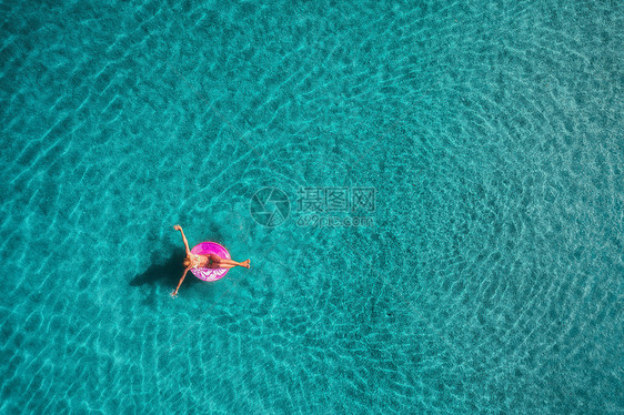 鸟瞰轻女子游泳粉红色的游泳环透明的绿松石海蓝色泻湖,土耳其奥卢德尼斯夏天的海景与女孩,蔚蓝的水早上无人机的顶部图片
