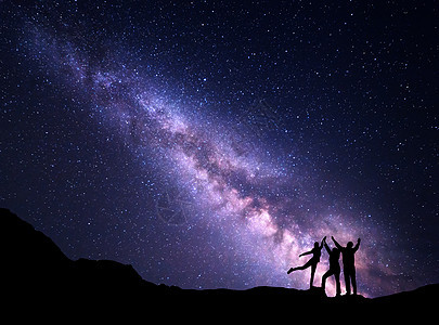 紫色银河的景观夜空中个幸福家庭的轮廓,山上举手臂美丽的宇宙太空背景图片