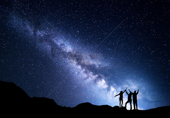 蓝色银河的景观夜空中个幸福家庭的轮廓,山上举手臂美丽的宇宙太空背景图片