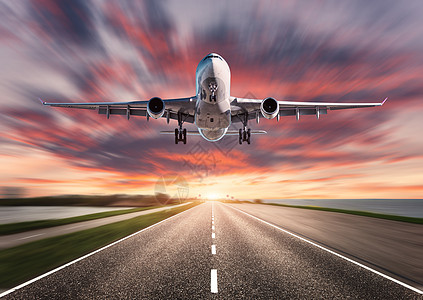 飞机道路日落时运动模糊效果旅客飞机的景观飞过沥青路五颜六色的天空商业飞机正降落背景模糊的飞机图片