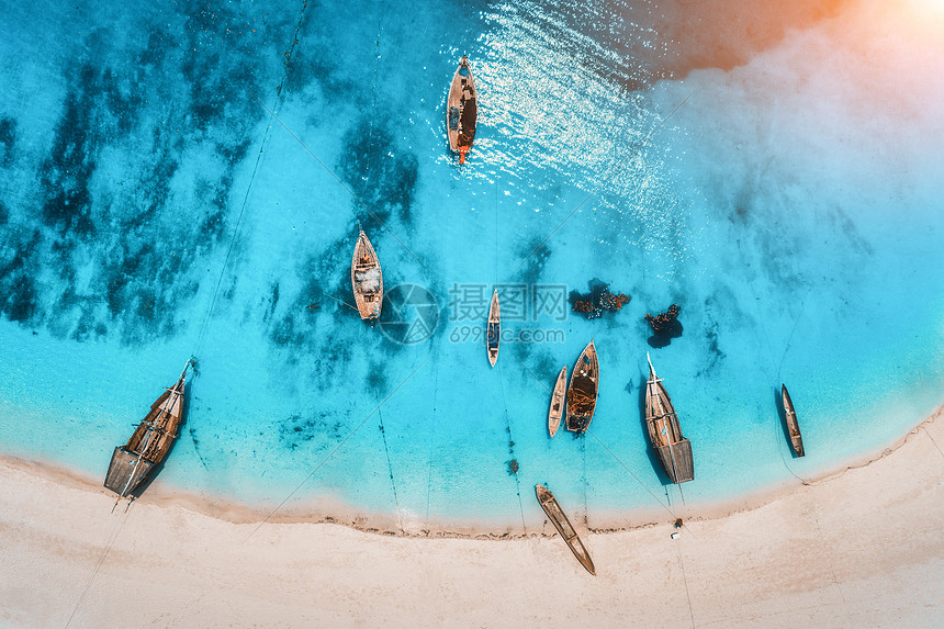 夏天的日落时,清澈的蓝色水中俯瞰渔船无人驾驶的船,沙滩上俯瞰印度洋非洲桑给巴尔旅行热带景观与帆船,图片