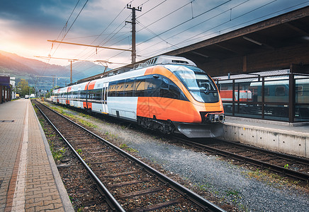 夏季日落时,山上火车站上的高速列车铁路站台上的橙色现代通勤列车铁路工业景观客运城际日落时分,火车站上的高速图片