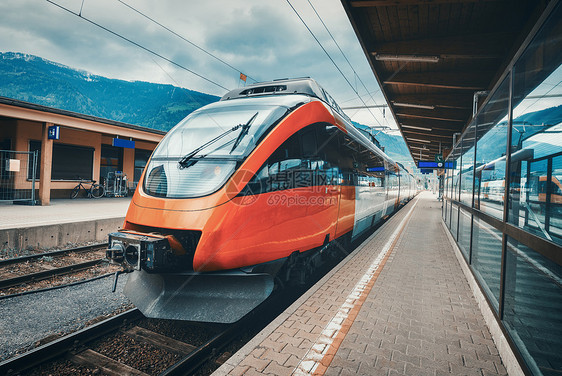夏季日落时,山上火车站上的高速列车铁路站台上的橙色现代通勤列车铁路工业景观客运城际日落时分,火车站上的高速图片