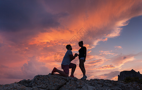 风景与个男人的剪影,向他的女朋友求婚,山峰上五颜六色的日落情人的剪影夫妇人,关系图片