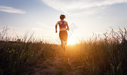 轻的运动女孩夏天的田野里日落时乡村的路上跑步生活方式体育背景图片