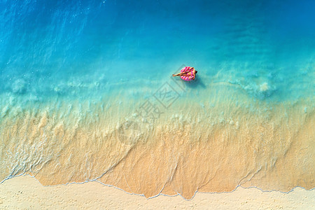 鸟瞰个轻的女人游泳与甜甜圈游泳环清澈的蓝色海洋与波浪日落夏天热带航空景观与女孩,蔚蓝的水,沙滩的风景旅图片
