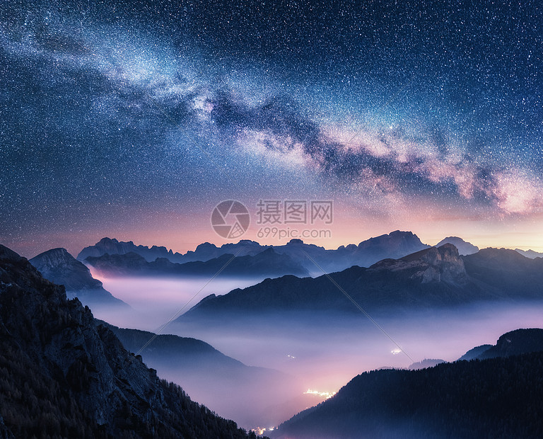 夏天的夜晚,银河雾中飞过群山景观雾的高山山谷,紫色的低云,五颜六色的银河星空,城市照明意大利白云石图片