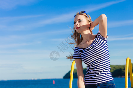 夏季放松肖像女孩与蓝色心形太阳镜享受夏季微风户外天空背景图片