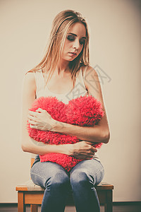 破碎的心的爱的悲伤幸的女人抱着红心枕头图片