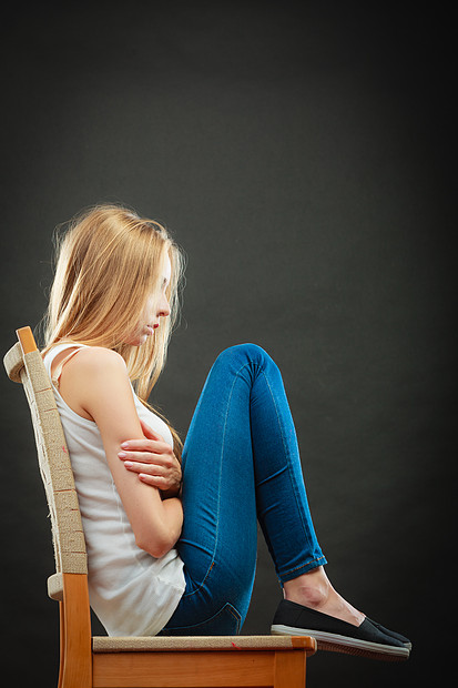 孤独消极情绪轻的悲伤的孤独的女人蜷缩椅子上