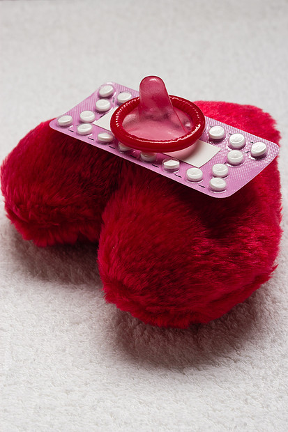 药物避孕爱节育口服避孕药避孕套红色心形小枕头上