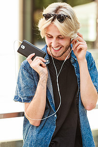 时尚男士站在街道边带着耳机听音乐图片