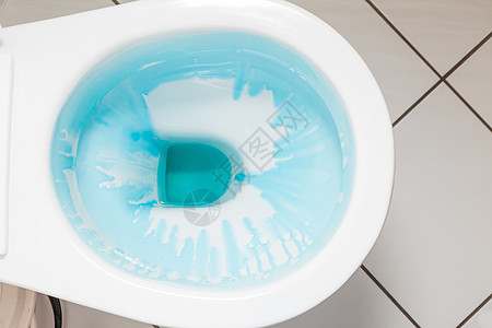 清洁消白色马桶用蓝色洗涤剂冲洗后白色马桶用蓝色洗涤剂背景图片