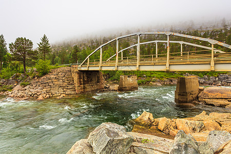 横跨山河的桥梁,挪威景观多云雾天,雨天挪威的saltfjeletsvartisen公园挪威山区河流上的桥梁图片