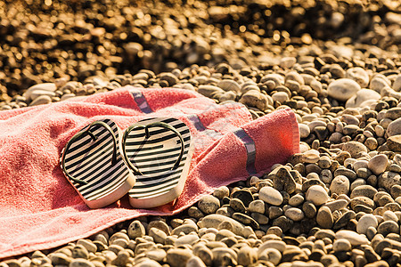 沙滩配件毛巾上进行日光浴鞋子凉鞋拖鞋,石头石头沙子拖鞋日光浴毛巾上图片