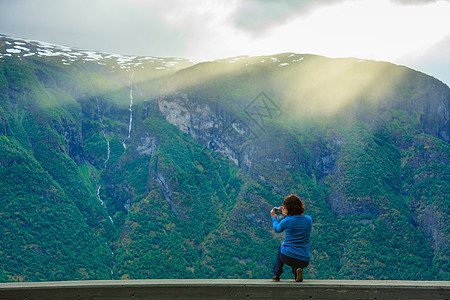 旅游旅行女游客用相机拍照,欣赏索格峡湾县的山脉峡湾景观挪威斯堪的纳维亚女游客挪威峡湾拍照图片