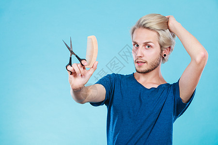 风格时尚轻时尚的男发型师理发师新的想法,改变外观金发男人用剪刀木梳创造发型,蓝色男人用剪刀梳子创造新的气图片