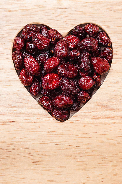健康高纤维食品,机营养蔓越莓干蔓越莓果木质表背景上呈心形图片