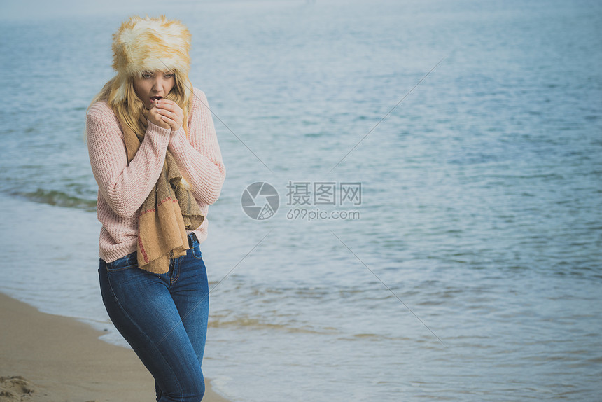 女人穿着温暖时尚的秋装 戴着毛茸茸的大帽子 但感觉很冷女海滩上放松散步时发冷穿着时尚服装的女海边感觉很冷高清图片下载 正版图片 摄图网