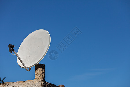 白色卫星碟,背景蓝天家庭屋顶上的电视天线无线技术数字设备蓝天上的卫星天线图片