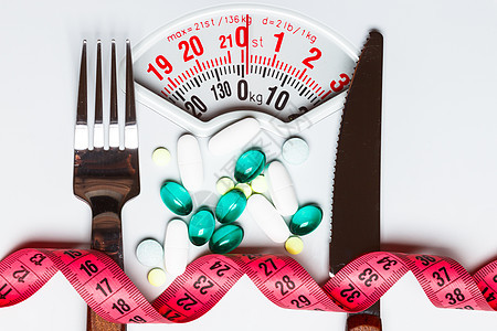 健康饮食医药保健食品补充剂减肥理念白色鳞片上测量胶带的药丸图片