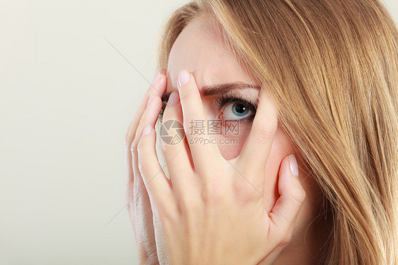 害怕的女人透过她的手指窥视灰色害羞的少女用手遮住脸图片