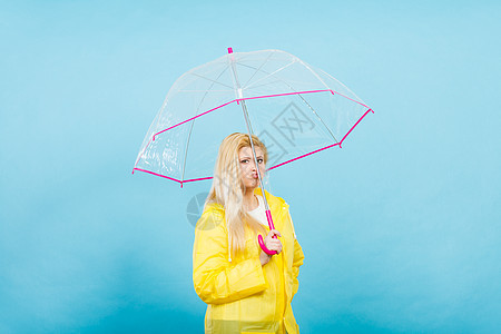 悲伤无聊的金发女人穿着黄色雨衣,着透明的雨伞等雨悲伤无聊的女人穿着雨衣,着雨伞图片