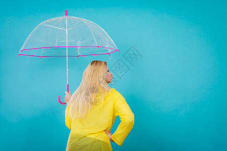 雨天秋日配饰理念金发女人穿着雨衣,着透明的伞,背景金发女人着透明的伞图片