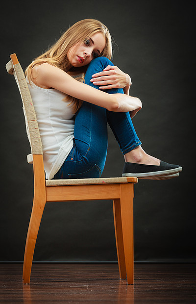 孤独消极情绪轻的悲伤的孤独的女人蜷缩椅子上图片