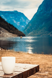 木桌上的杯子美丽的峡湾挪威斯堪的纳维亚背景,湖泊山脉木桌上的杯子,挪威峡湾景观图片