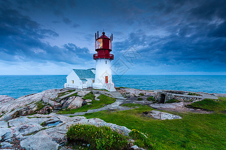 历史上红色白色灯塔岩石海岸边缘,南挪威,林德斯尼斯FYR信标挪威的林德斯尼斯灯塔图片