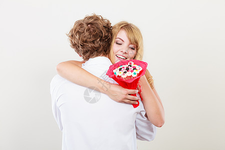 充满爱意的夫妇抱着糖果花漂亮的女人感谢男人的礼物爱的夫妇与糖果花拥抱爱背景图片