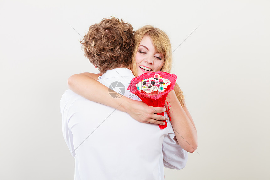 的夫妇抱着糖果花漂亮的女人感谢男人的礼物爱的夫妇与糖果花拥抱爱