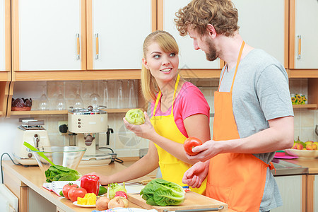 快乐的轻夫妇饭女人男人家里的现代厨房里玩得很开心,同时准备新鲜蔬菜食物沙拉图片