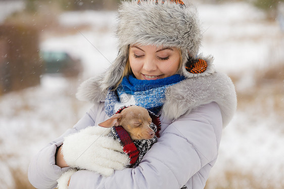 轻的女人用温暖的毯子围巾把她最好的朋友小狗包裹来,寒冷的雪天里温暖他动物保护拯救收养女人拥抱温暖她的小狗图片