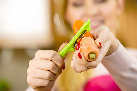女人用食物剥皮机剥蔬菜烹饪女上菜前先准备胡萝卜图片