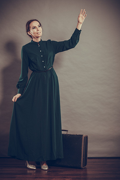 女人复古风格的深绿色长袍与旧手提箱复古照片