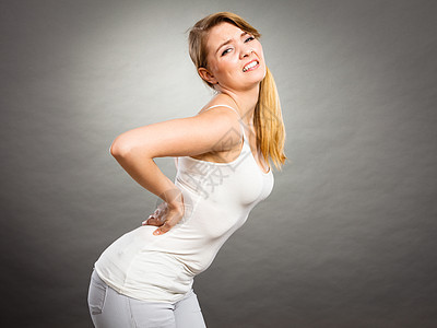 长时间的工作时间健康背痛的轻女患背部疼痛的女人灰色患背痛的女人图片