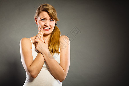 牙科护理牙痛轻的女人疼痛的女孩患可怕的牙齿疼痛,用手掌抚摸她的脸颊图片