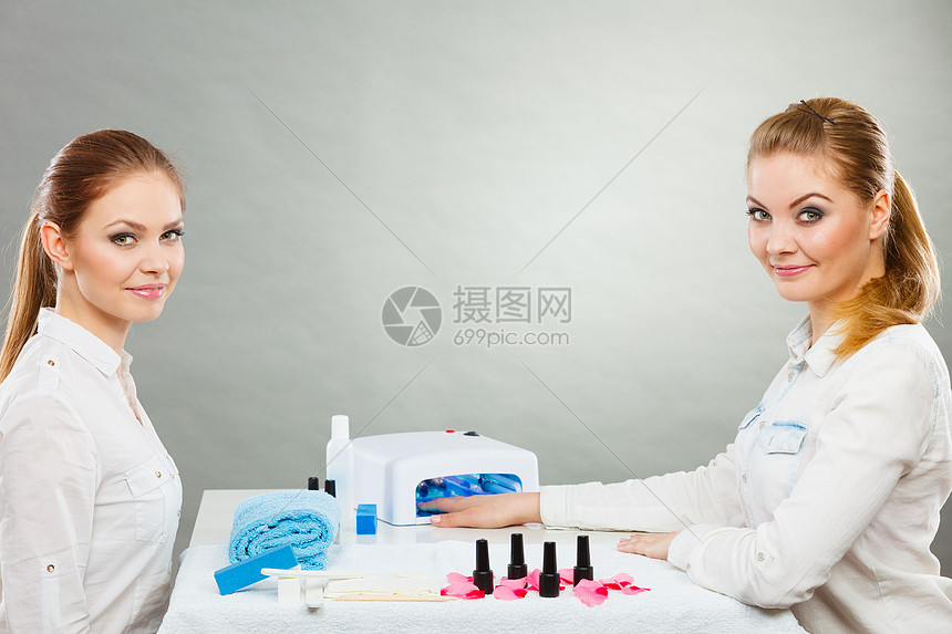 美甲工艺美容院的轻美容师女顾客女客户手握桌上的指甲油 毛巾文件照明仪器专业美甲师绘画女指甲高清图片下载 正版图片 摄图网