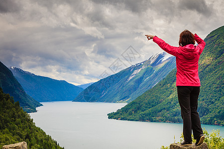 旅行游客女人用手指看着挪威峡湾美丽的山脉景观挪威山脉峡湾的女游客图片