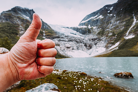 人的手像用拇指手势雪山的背景与冰川,认可旅行的男的手像拇指山上的背景图片