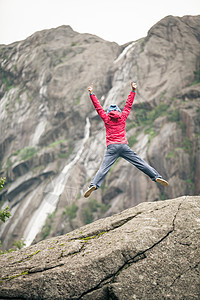 快乐的女人灰色的山上跳上岩石,享受旅行冒险快乐的女人山上跳上岩石图片