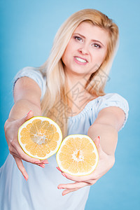 女人微笑的女孩手里着两个半黄葡萄柚柑橘类水果,蓝色的健康的食物,节食的女人手里着葡萄柚柑橘类水果图片