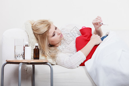 疾病,季节病问题的患流感的女人躺沙发上看温度计上的温度躺沙发上患流感的女人生病了图片