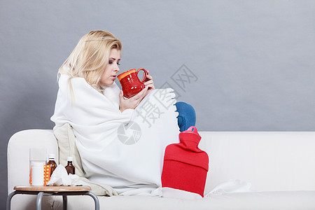 疾病,季节病问题的患流感的女人躺沙发上,着杯子,着热饮料图片