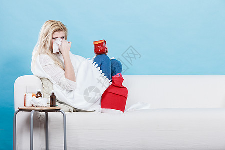 疾病,季节病问题的患流感的女人躺沙发上打喷嚏,打纸巾躺沙发上患流感的女人生病了图片