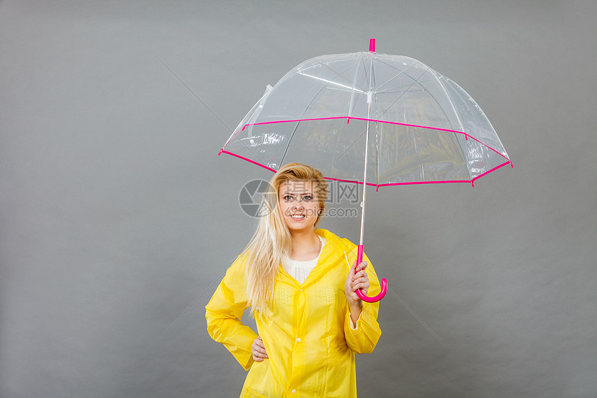 雨天的好心情快乐的金发女人穿着黄色雨衣,着透明的雨伞快乐的女人穿着雨衣,着透明的雨伞图片